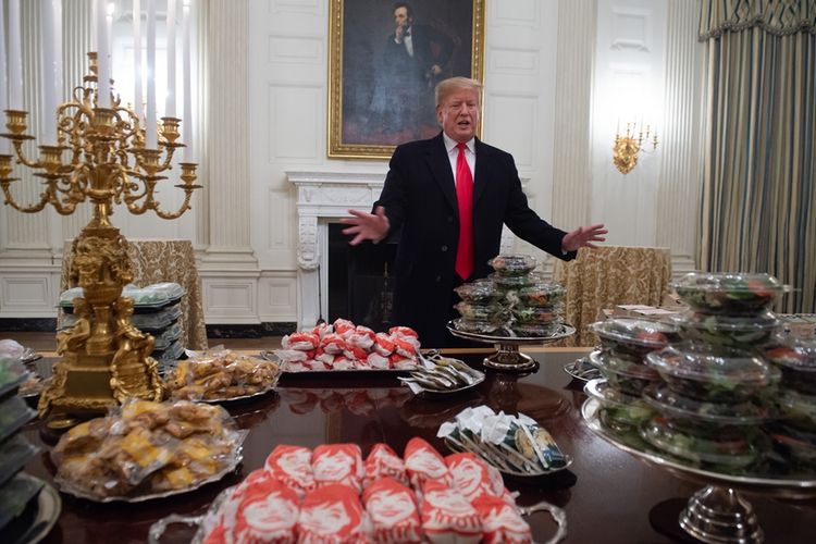 Presiden AS Donald Trump menunjukkan meja makan penuh dengan makanan cepat saji ala Amerika, yang akan disajikan untuk tim juara liga football nasional, Clemson Tigers, di ruang makan Gedung Putih, Senin (14/1/2019) malam.