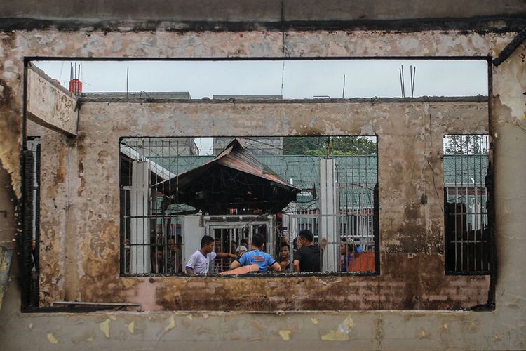 Petugas gabungan berjaga di depan puing bangunan Rutan yang hangus terbakar pasca-kerusuhan di Rutan Kelas II B Siak Sri Indrapura, Kabupaten Siak, Riau, Sabtu (11/5/2019). Kericuhan diduga dipicu pemukulan oleh petugas lapas terhadap seorang tahanan.