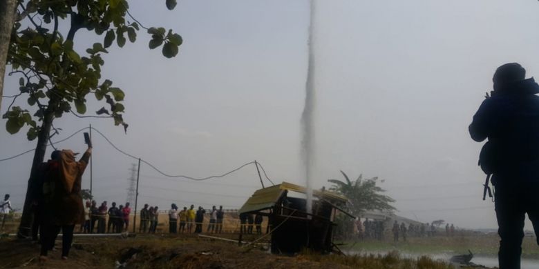 Nampak seorang warga berswafoto di semburan air disertai gas yang muncul di area persawahan Desa Sidolaju, Kecamatan Widodaren, Kabupaten Ngawi, Jawa Timur, Rabu ( 8/8/2018).