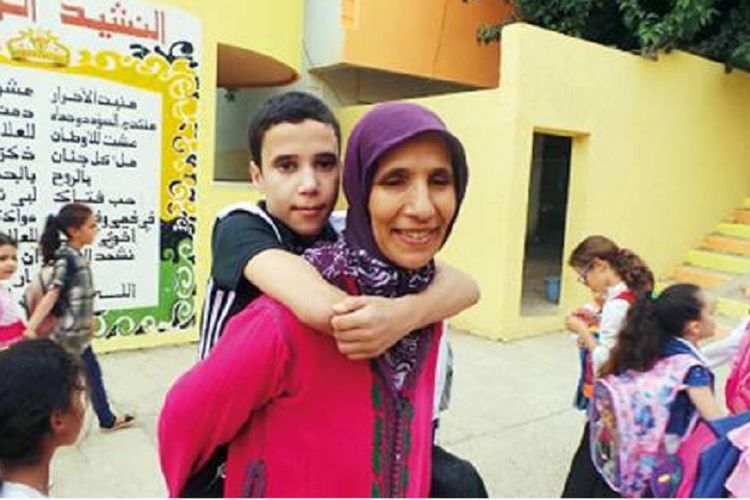 Sejak lima tahun lalu Rabiaa Roumaili menggendong putranya Radwan yang kehilangan dua kakinya setelah diamputasi akibat meningitis ke sekolah.