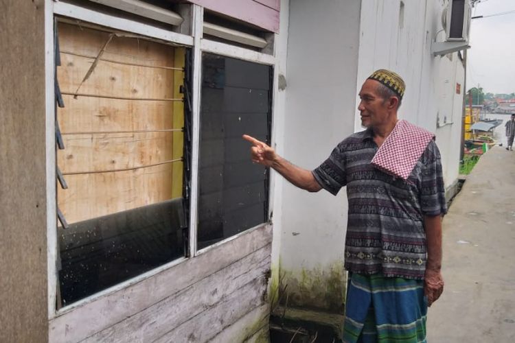 Salah satu warga Lorong Hijriah RT 17 RW 05 Kelurahan 3-4 Ulu, Keamatan Seberang Ulu  1 menunjukkan kaca rumah mereka yang pecah akibat terkena dampak dari meledaknya perahu jukung Jasa Mulya di perairan Sungai Musi Palembang, Sumatera Selatan, Jumat (21/12/2018).