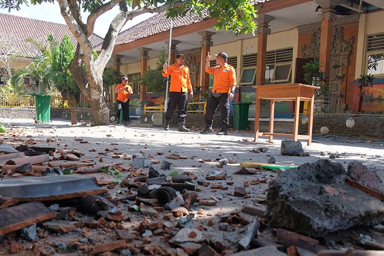 Petugas BPBD Badung memeriksa kondisi bangunan SD No. 1 Ungasan  yang rusak di bagian atap akibat gempa bumi di Badung, Bali, Selasa (16/7/2019). Gempa berkekuatan magnitudo 6 (selanjutnya dilakukan pemutakhiran menjadi magnitudo 5,8) yang berlokasi di wilayah Samudera Hindia Selatan Bali-Nusa Tenggara tersebut mengakibatkan genteng sekolah runtuh sehingga menyebabkan seorang guru dan tiga siswa terluka.