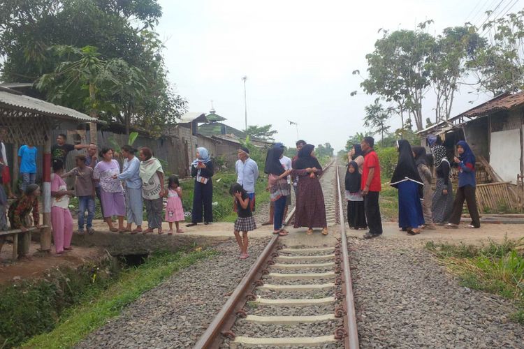 Warga berjalan di jalan gang yang melintasi rel kereta api jurusan Sukabumi-Cianjur di Kampung Ciandam, Cibeureum, Sukabumi, Jawa Barat, Minggu (12/8/2018). 