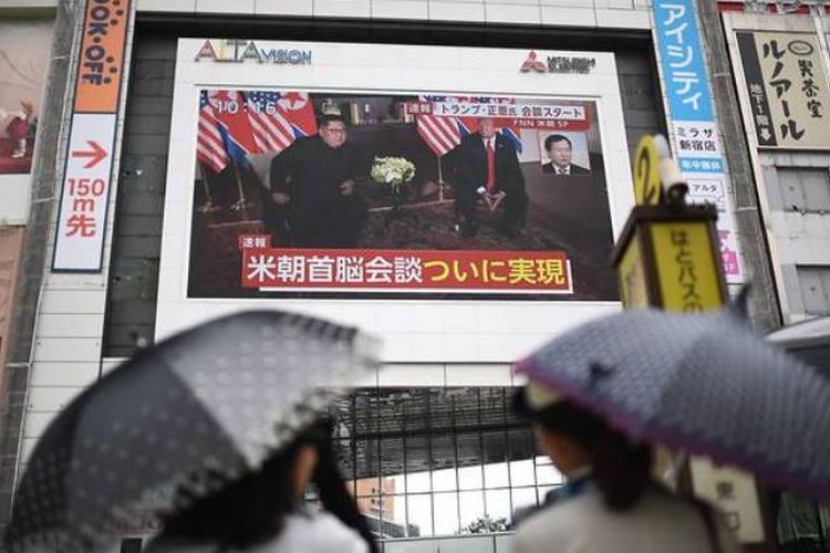 Pejalan kaki di Jepang berhenti di depan layar besar yang menyiarkan siaran langsung pertemuan Presiden AS Donald Trump dengan Kim Jong Un.