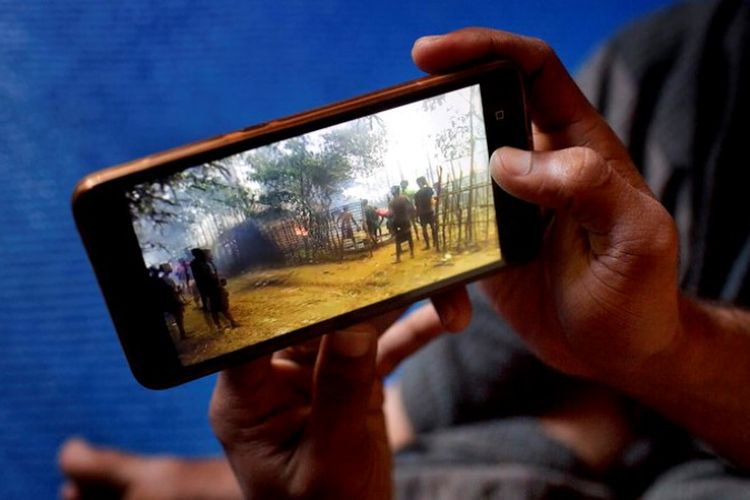 Salah satu pengungsi Rohingya di kamp Bangladesh melihat rekaman tentang kampung halamannya melalui telepon genggam.