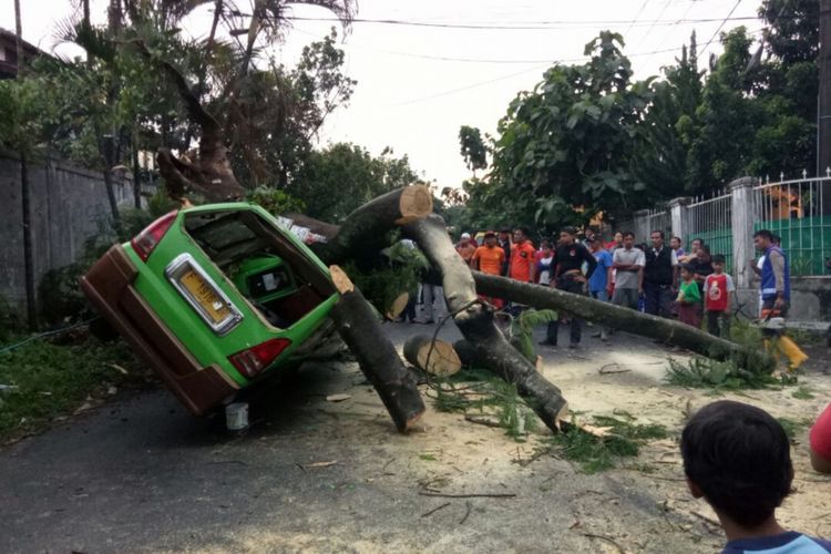 Sebuah angkot jurusan Pajajaran-Pasar Bogor rusak parah setelah tertimpa pohon tumbang di Perumahan Baranangsiang Indah, Kelurahan Katulampa, Kecamatan Bogor Timur, Kota Bogor, Minggu (19/11/2017). 