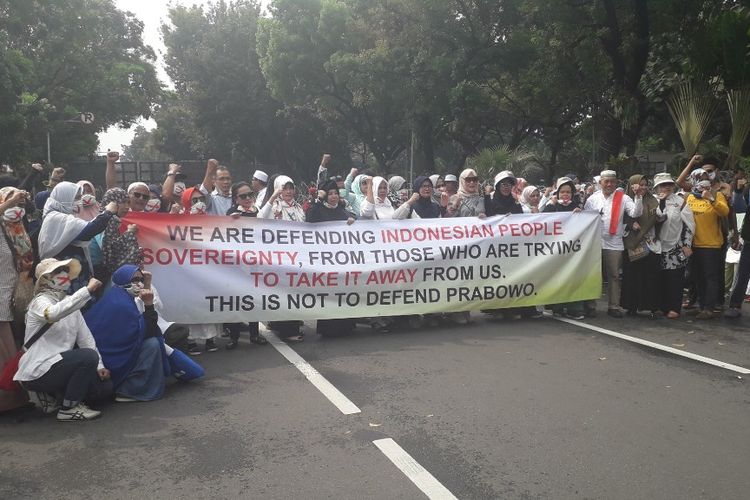 Massa pengunjuk rasa membentangkan spanduk berisi aspirasi mereka di Jalan Medan Merdeka Barat dekat Gedung MK, Jumat (14/6/2019).