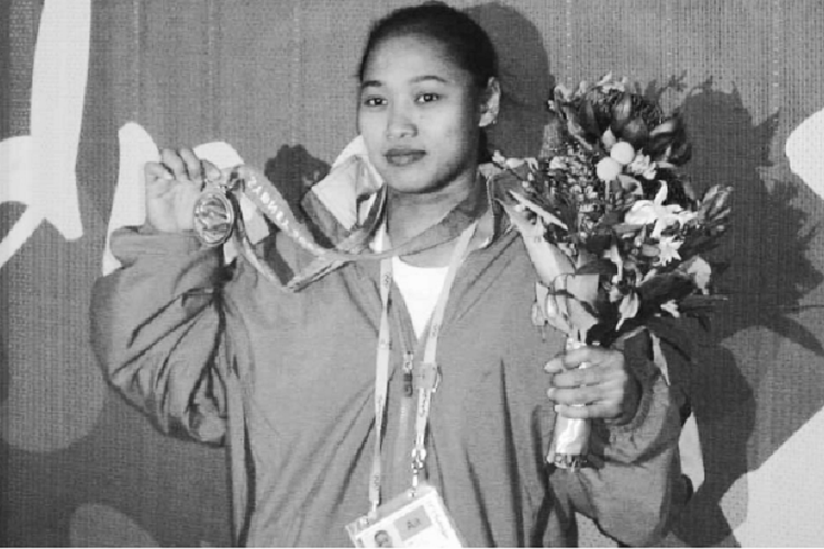 Lifter putri Indonesia, Winarni, berpose di hadapan para wartawan menunjukkan medali perunggu di tangan kanan, dan rangkaian bunga di tangan kiri, setelah upacara pengalungan medali di Sydney pada Senin, (18/9/2000).