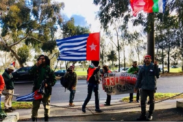 Pengunjuk rasa mengibarkan bendera kelompok Papua Barat Merdeka di depan kantor KJRI Melbourne.