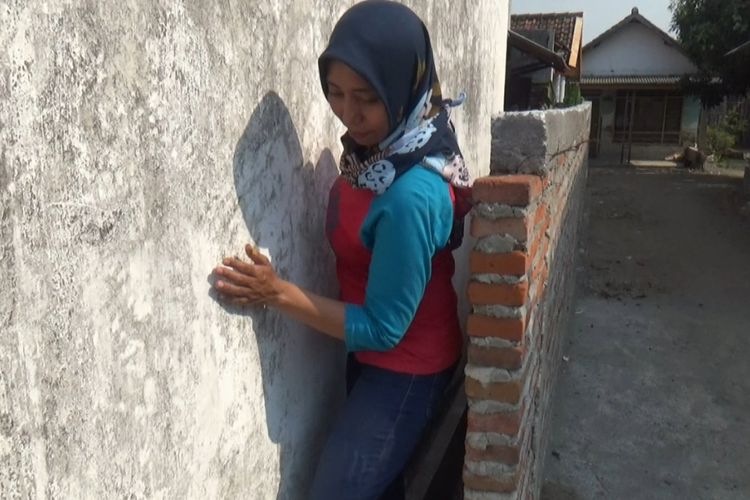 Siti Khotijah, warga Desa Sudimoro, Megaluh, Jombang, Jawa Timur, saat keluar dari rumah melalui celah antara rumah kerabatnya dengan tembok yang dibangun tetangganya.