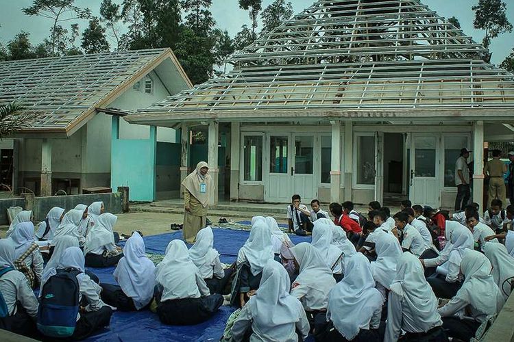 Guru memberikan motivasi kepada siswa kelas IX SMP N 1 Kalibening, Banjarnegara, Jawa Tengah sebelum melaksanakan ujian nasional di tenda darurat, Senin (23/4/2018). Gedung sekolah tersebut mengalami kerusakan berat pasca-gempa tektonik lokal yang terjadi pada Rabu, 18 April lalu.