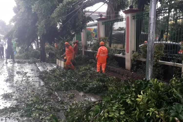 Petugas PPSU membersihkan potongan-potongan pohon tumbang di depan Gelanggang Remaha Jakarta Timur, Selasa (30/4/2019).