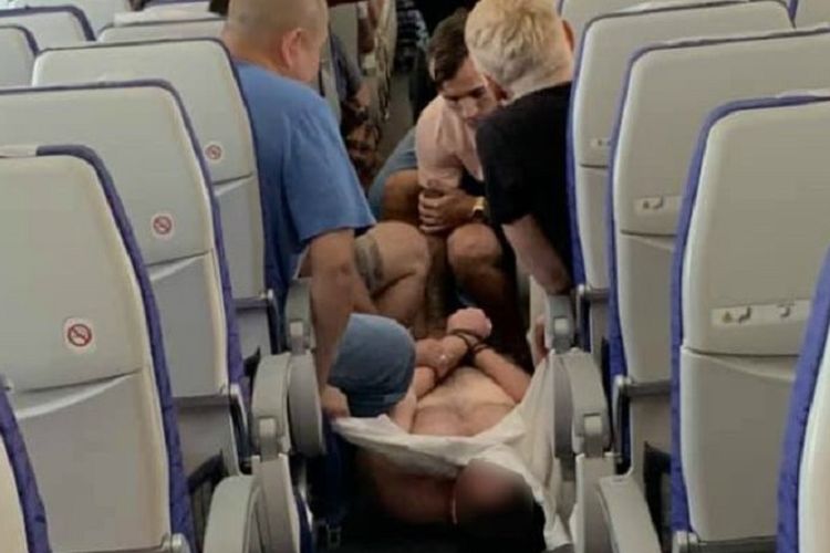 Foto ini memperlihatkan para penumpang maskapai Scoot dari Gold Coast menuju Singapura mengamankan seorang pria yang mengamuk dan menyerang penumpang lainnya.