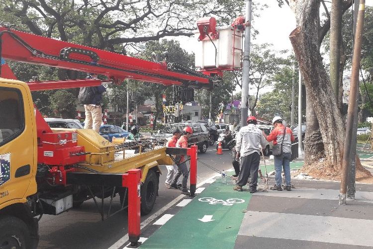 Sejumlah petugas Suku Dinas Perindustrian dan Energi Jakarta Pusat melakukan pencopotan tiang - tiang penerangan jalan umum (PJU) di Jalan Asia Afrika, Jakarta Pusat pada Rabu (1/8/2018).