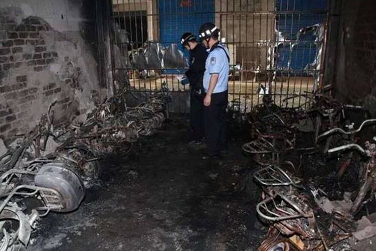 Petugas pemadam kebakaran dan polisi memeriksa sisa-sisa skuter yang hangus dalam insiden kebakaran di gedung asrama mahasiswa di Guangxi, China, Minggu (5/5/2019).