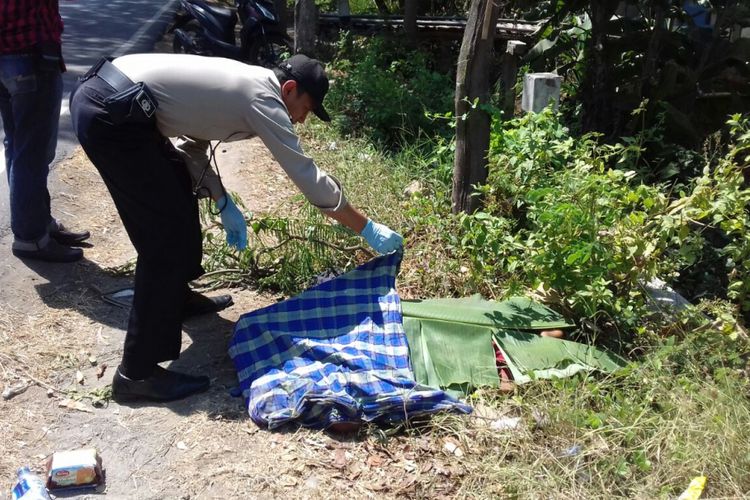 Aparat Polres Ponorogo membuka penutup yang menutupi jenazah korban yang ditemukan tewas di ruas jalan raya Ponorogo - Pacitan di Desa Beton, Kecamatan Siman, Kabupaten Ponorogo, Senin ( 21/8/2017) siang.