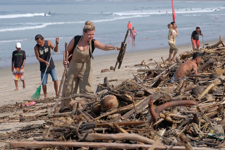 Wisatawan mancanegara turut membersihkan sampah yang terdampar akibat cuaca buruk di Pantai Kuta, Badung, Bali, Senin (11/2/2019). Hujan deras disertai angin kencang yang melanda Bali berdampak pada arus laut yang terus membawa sampah dari daerah lain dan terdampar sejumlah pantai bagian selatan Bali.