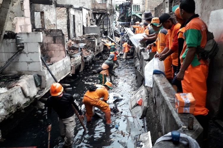 Sejumlah petugas Penanganan Prasarana dan Saranan Umum (PPSU) membantu membersihkan saluran air dan benda-benda bekas kebakaran di Jalan Tomang Raya, Grogol Petamburan, Jakarta Barat pada Selasa (22/1/2019).