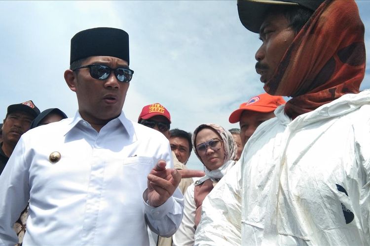 Gubernur Jawa Barat Ridwan Kamil berbicara dengan warga yang ikut membersihkan limbah minyak saat meninjau lokasi terdampak di Desa Cemarajaya, Kecamatan Cibuaya, Kabupaten Karawang, Rabu (7/8/2019).