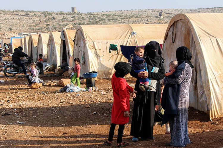 Perempuan dan anak-anak terlihat di luar tenda di kamp Furat (Efrat) untuk orang-orang yang kehilangan tempat tinggal dari Deir Ezzor, sebelah utara kota Kafr Dariyan di provinsi utara Idlib, Suriah. Foto diambil pada 27 November 2017.