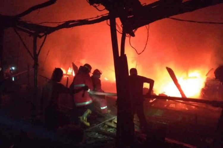 Petugas dari Pemadam Kebakaran saat berupaya memadamkan api yang melahap 15 perahu nelayan di Indramayu, Jawa Barat, Jumat (21/6/2019). 