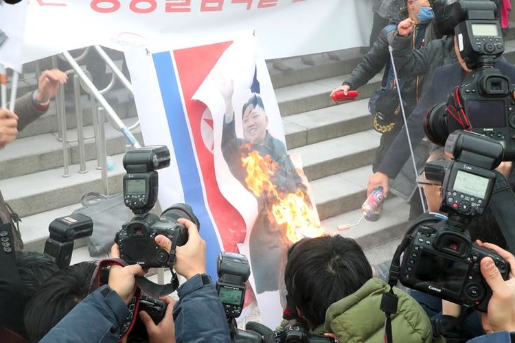 Massa Korea Selatan membakar bendera dan foto Pemimpin Korea Utara, Kim Jong Un, dalam unjuk rasa yang berlangsung di Seoul Senin (22/1/2018). Mereka memprotes rencana pembentukan tim gabungan hoki es perempuan.