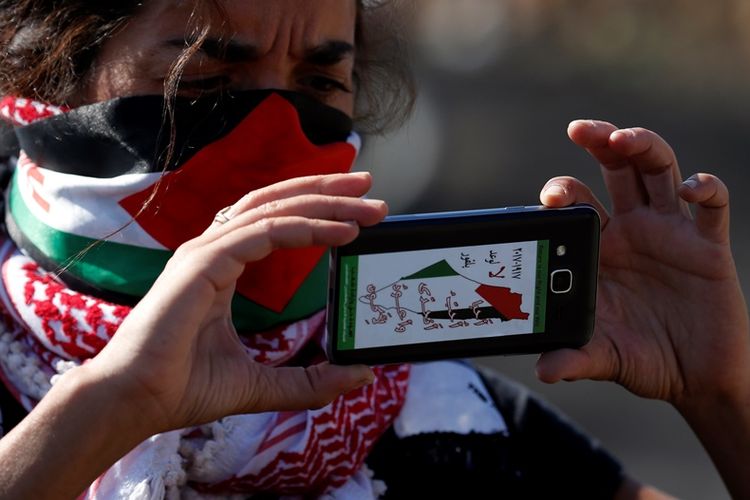 Seorang warga Palestina mengambil gambar menggunakan telepon genggamnya dalam salah satu unjuk rasa menentang pendudukan Israel.