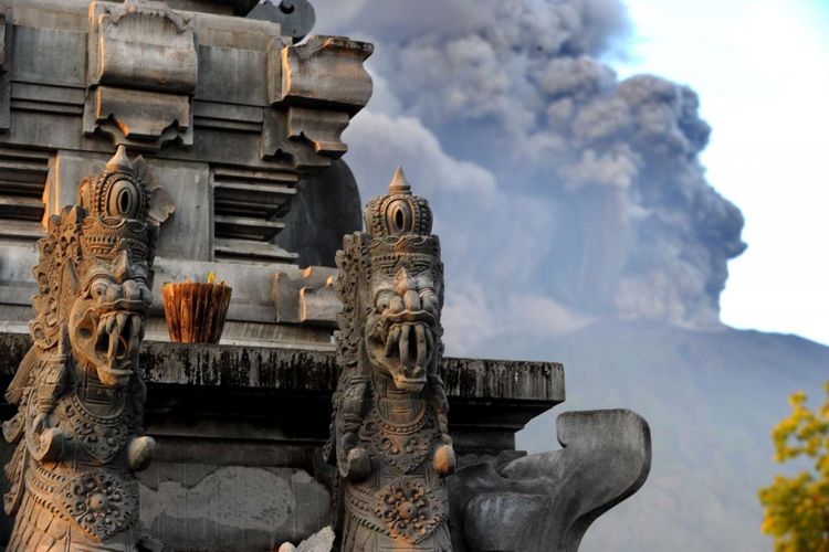 Erupsi Gunung Agung terlihat dari salah satu Pura di Kubu, Karangasem, Bali, 26 November 2017. Gunung Agung terus menyemburkan asap dan abu vulkanik dengan ketinggian yang terus meningkat, mencapai ketinggian 3.000 meter dari puncak. Letusan juga disertai dentuman yang terdengar sampai radius 12 kilometer.