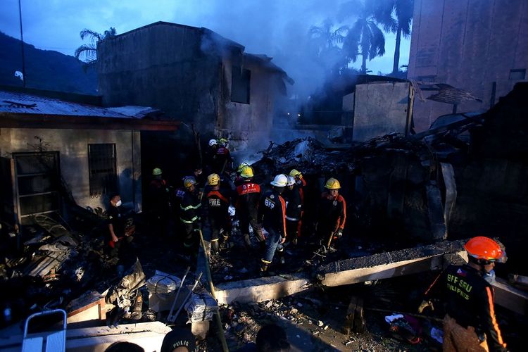 Petugas pemadam kebakaran memeriksa lokasi jatuhnya pesawat ambulans di kota Calamba, Filipina, Minggu (1/9/2019).