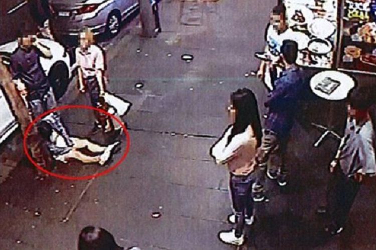 Dalam gambar, para pejalan kaki mengerumuni seorang perempuan (bertanda merah) yang dicampakkan di trotoar akibat mabuk pada 9 November 2017.