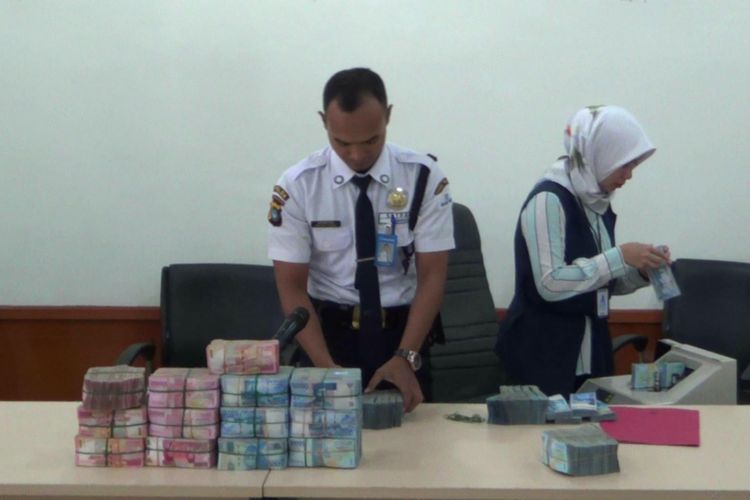 Petugas dari Bank Rakyat Indonesia saat menghitung uang denda dari perusahaan tambang timah di kantor Kejaksaan Negeri Pangkal Pinang, Rabu (6/6/2018)