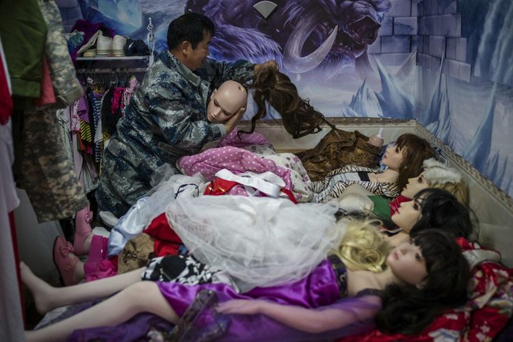 Yu Zhenguo ketika memakaikan baju ke salah satu boneka seksnya. Pria 60 tahun asal China itu berujar dia menganggap boneka itu sebagai anak sendiri.