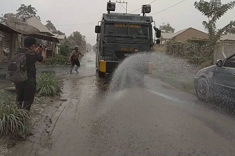 Mobil water canon Polres Tanah Karo menyirami jalan-jalan desa yang tertutup debu Sinabung, Senin (19/2/2018).