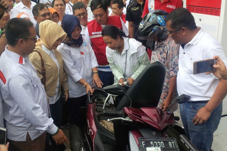  Menteri BUMN, Rini Soemarno (tiga kanan) sedang mengisikan bahan bakar pertalite ke sepeda motor di sela peresmian BUMN Shop di Sukabumi, Jawa Barat, Sabtu (22/12/2018). 