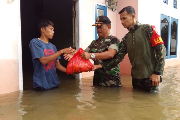 Danramil 07/Kampar Kapten Inf Lilik Haryono dan satu orang prajuritnya menyerahkan bantuan sembako kepada korban banjir di Dusun II Langgam, Desa Alam Panjang, Kampar, Riau, Jumat (14/12/2018).