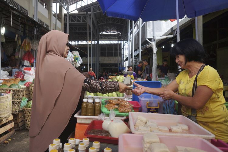 Transaksi Nurmala (kanan) yang berjualan tahu dengan pelanggannya di pasar Peunayong, Desember 2017.