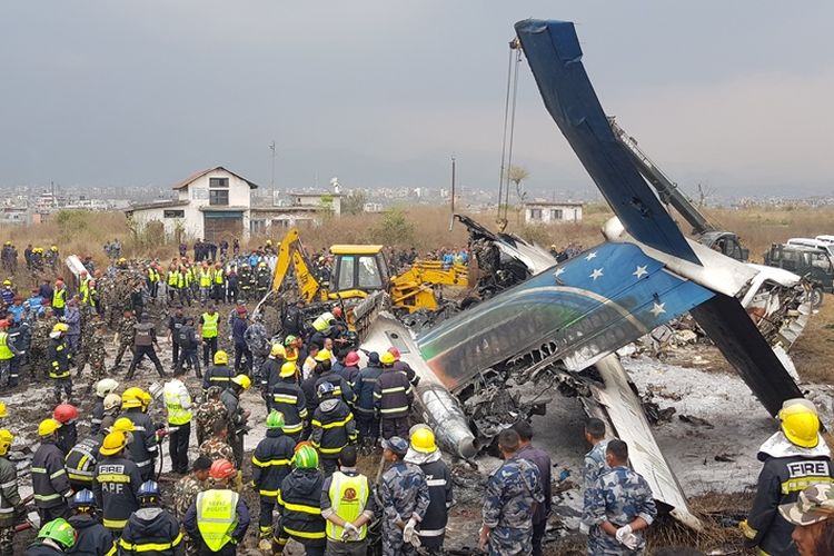Tim penyelamat berkerumun di sekitar reruntuhan pesawat Bombardier milik maskapai penerbangan US-Bangla yang jatuh di bandara Tribuvhan, Kathmandu, Nepal, Senin (12/2/2018).