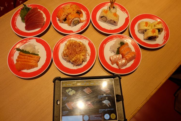 Memesan hidangan dengan memilih dari menu tablet di Genki Sushi. 