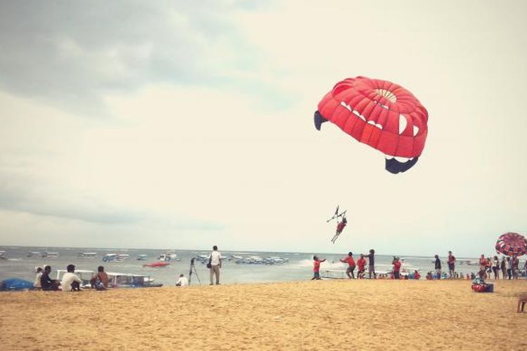 Wisatawan sedang parasailing di Pantai Tanjung Benoa, Bali.