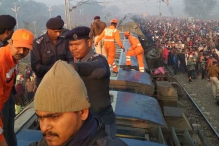 Petugas memeriksa gerbong kereta api yang terbalik usai tergelincir keluar jalur di India, Minggu (3/2/2019).