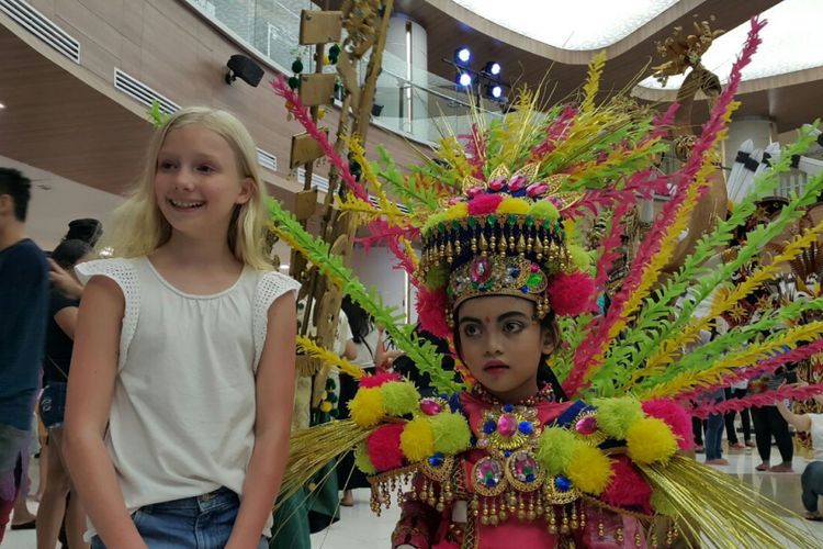 Zahra, salah satu peserta Jember Fashion Carnaval, berfoto dengan wisatawan mancanegara seusai gelaran karnaval di Lippo Mall Kuta, Bali, Jumat (29/9/2017).