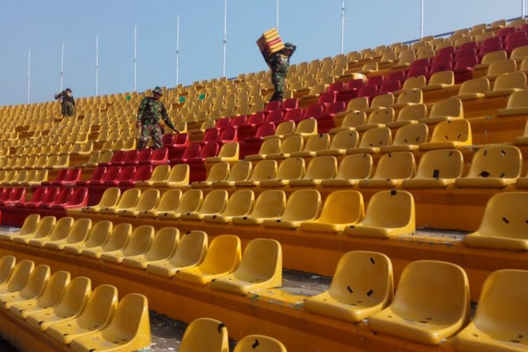 Bayalton Zikon Kodam II Sriwijaya mengumpulkan kursi yang rusak di stadion Glora Jakabaring, Palembang, akibat kerusuhan suporter, Senin (23/7/2018)