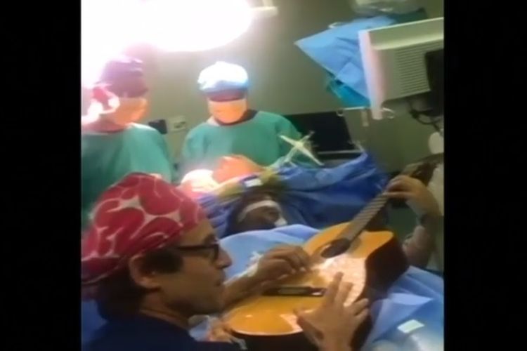 Pasien, Musa Manzini, memainkan gitar di tengah proses operasi pengangkatan otak dengan prosedur awake craniotomy yang dilakukan di sebuah rumah sakit di Durban, Afrika Selatan.
