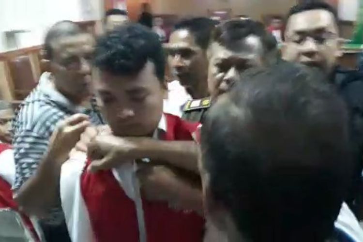 Tampak Terdakwa kasus pembunuhan satu keluarga di Bekasi, Haris Simamora digiring keluar ruangan sidang Pengadilan Negeri Bekasi usai jalani sidang kedua, Senin (18/3/2019).