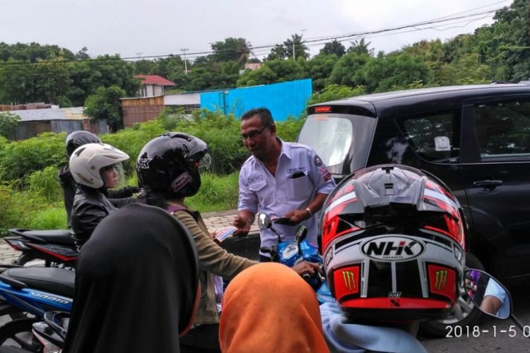 Komisioner KPU Kota Kupang, Nusa Tenggara Timur (NTT) Dany Ratu sedang membagikan brosur tentang sosialisasi Pilgub NTT kepada para pengendara kendaraan bermotor di Kota Kupang, Jumat (5/1/2017)