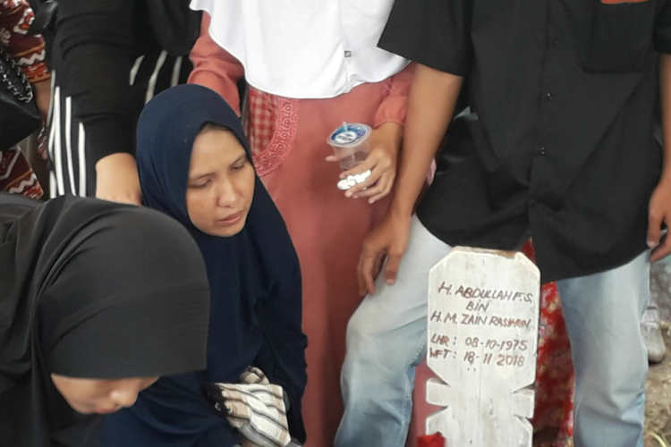 Istri Dufi, Bayu Yuniarti Hendriani, terlihay sembab dan menangis dalam prosesi pemakaman suaminya di TPU Semper, Jakarta Utara, Senin (19/11/2018) pagi.