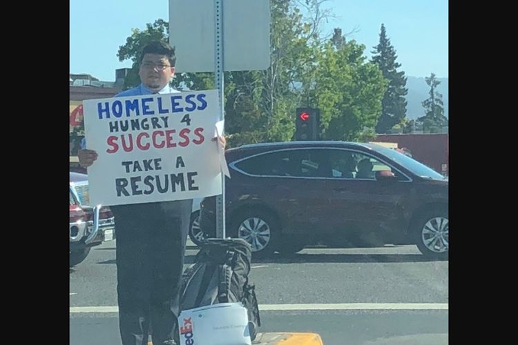 David Casarez (26) berdiri di tepi jalan di California sambil membawa papan karton dan membagikan selebaran daftar riwayat pekerjaan.
