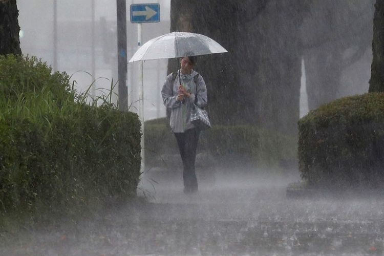 Seorang warga berjalan kaki di tengah hujan lebat di Kirishima, Prefektur Kagoshima, Jepang barat daya, Rabu (3/7/2019).