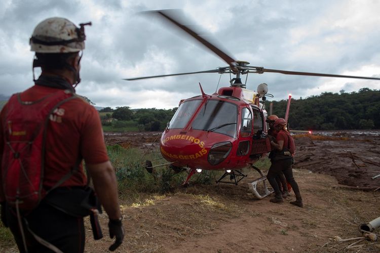 Petugas dari tim pemadam kebakaran Minas Gerais mengangkut jenazah yang ditemukan ke dalam helikopter, saat proses pencarian dan penyelamatan di lokasi bencana bendungan runtuh di Brasil, Sabtu (26/1/2019).