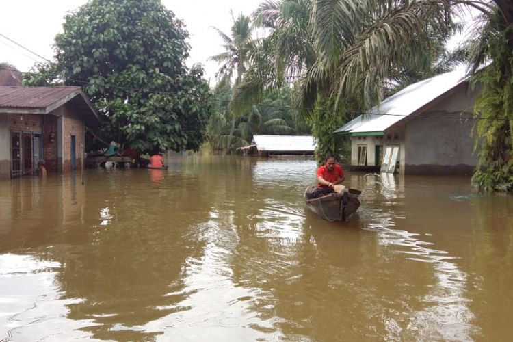 Warga korban banjir di Desa Buluh Cina, Kecamatan Siak Hulu, Kabupaten Kampar, Riau, keluar rumah menggunakan sampan, Senin (17/12/2018). 